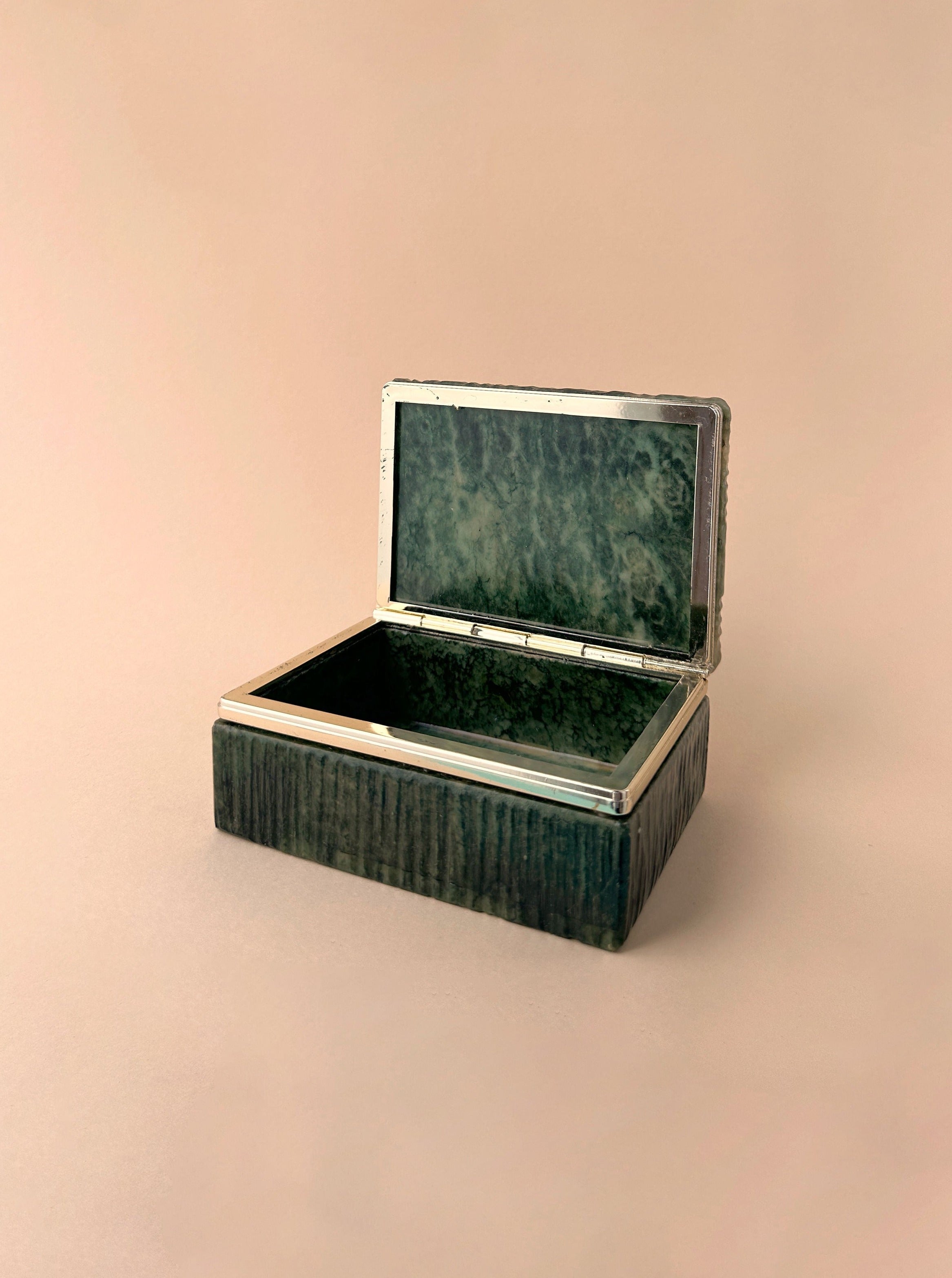An open, rectangular, vintage Dodo Vintage Italian Green Marble Case 70s jewellery box with a marbled green interior, set against a soft pink background.