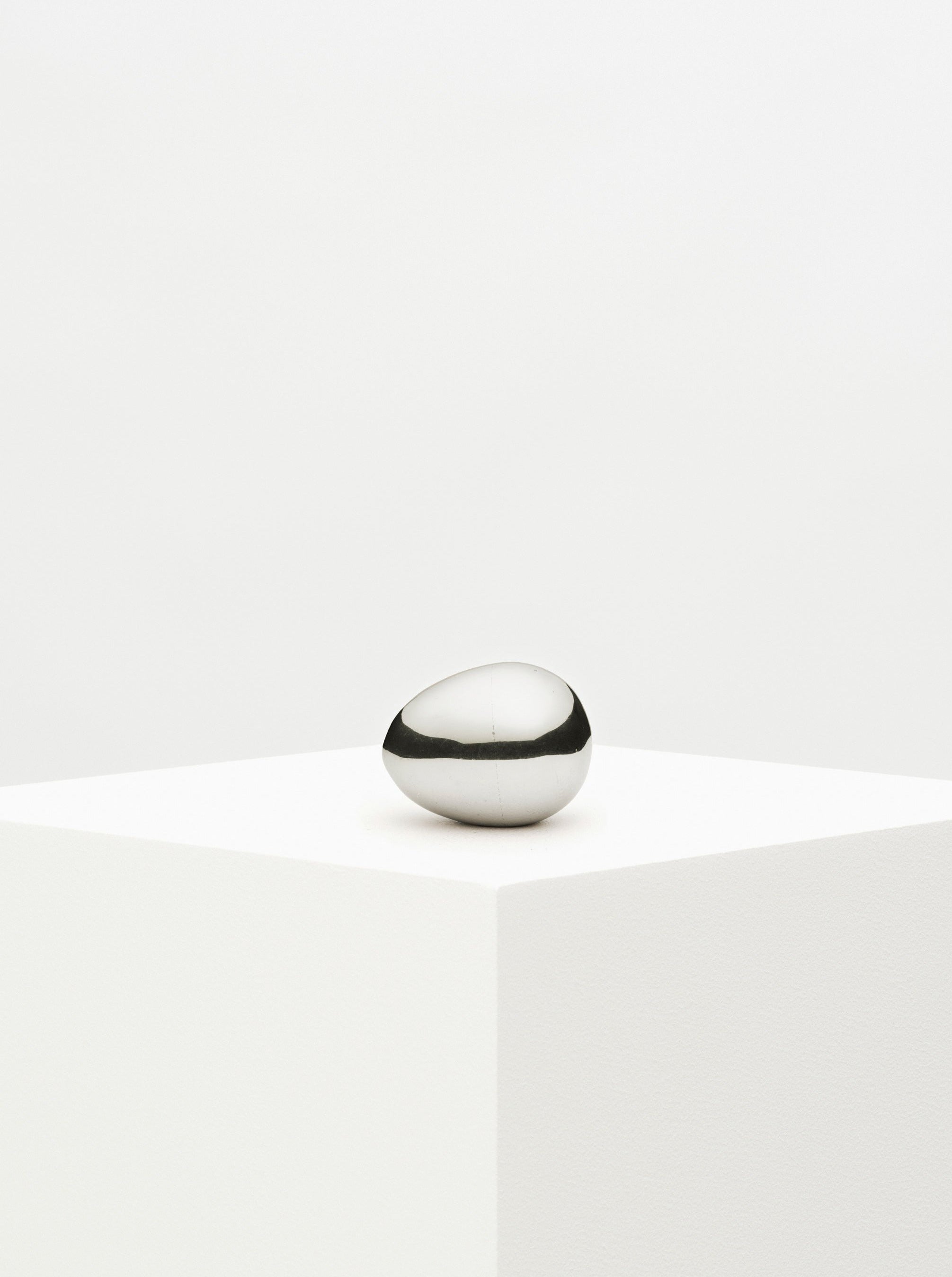 Silver egg paperweight on a marble surface with intricate design details