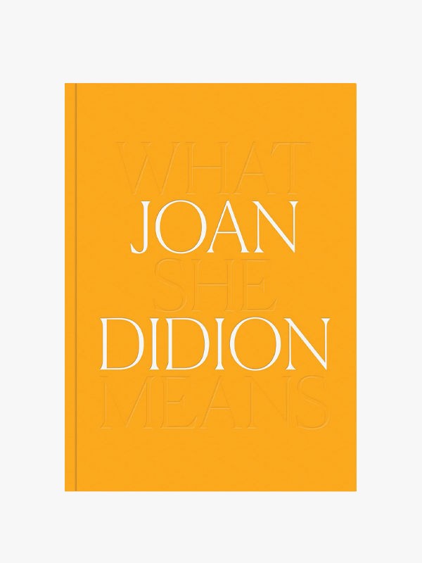 A bright orange book cover titled "Joan Didion" with faint embossed text in the background that reads, "What She Means." The title is in large white uppercase letters centered on the cover.