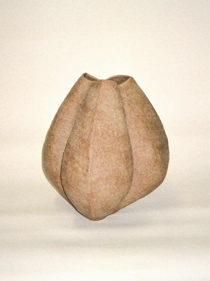 The Growing Vase n.2 by Aiste Bagdonaite is a hand built, light brown stoneware vase with a smooth matte finish and an organic geometric shape, shown against a plain white background. This sculptural piece is truly one-of-a-kind.