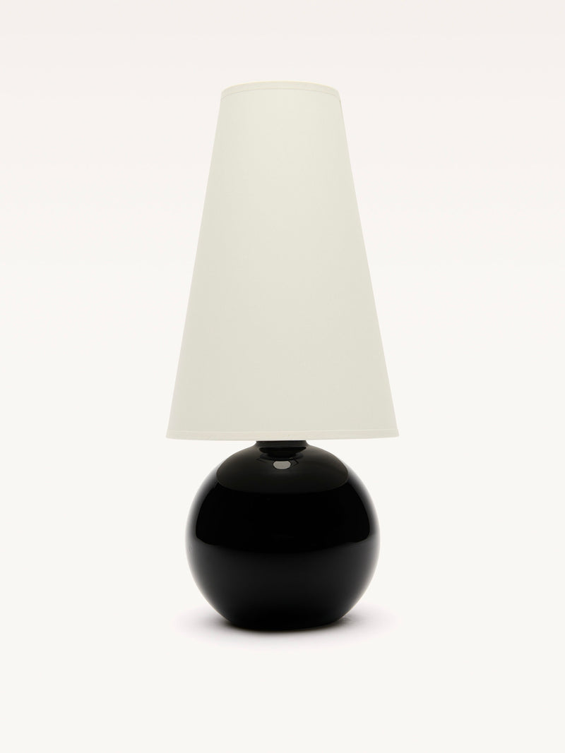 The Large Black Opalin Glass Lamp by Galerie MLS has a sleek black spherical base and a tall white cylindrical shade. A subtle brass ring adds to its modern design, making it a striking centerpiece against a white background.