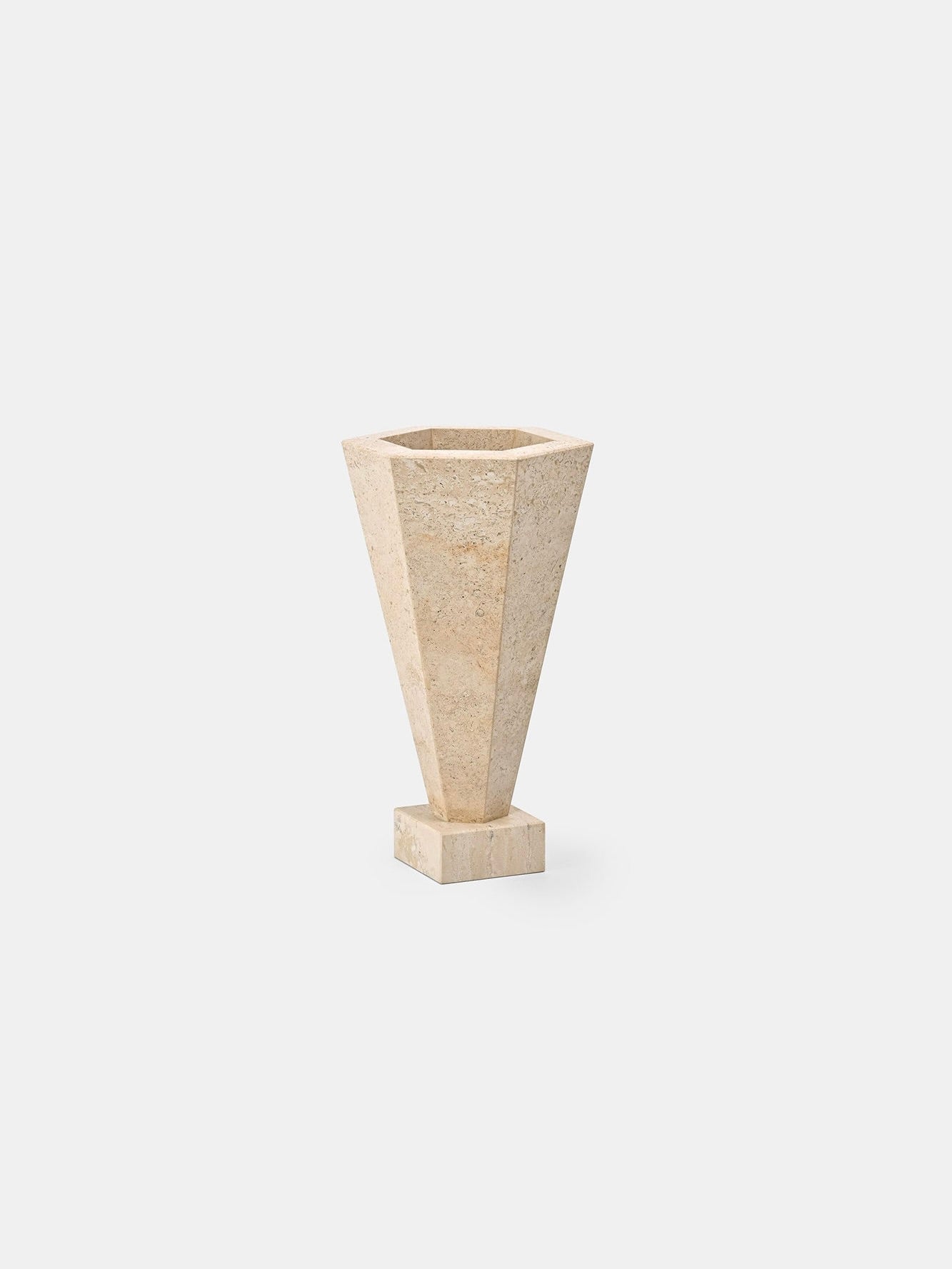 Part of Studio Vraco's collection, the Vase 01 Travertine tall geometric vase features a beige travertine finish with a narrow base and a wide hexagonal opening. Its textured appearance beautifully contrasts against a plain white background.