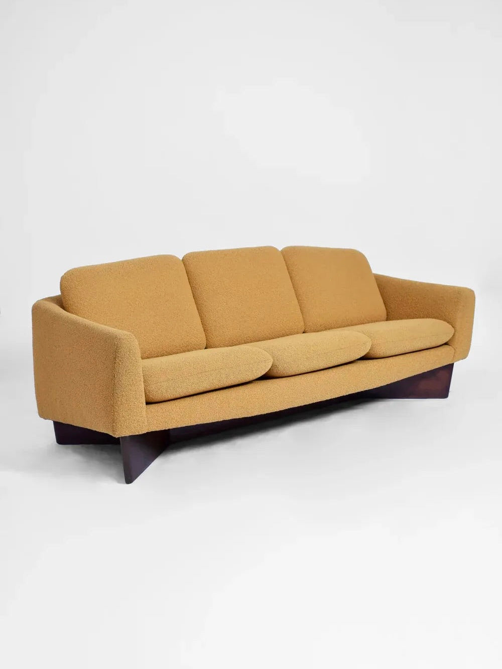 This Dangles and Defrance Yellow Sofa from the 1960s, offered by Barracuda Interiors, exemplifies mid-century modern style with its mustard-colored bouclé fabric upholstery. As part of the Burov edition, it features three comfortable cushions, sleek low armrests, and a wooden base set against a clean white background.