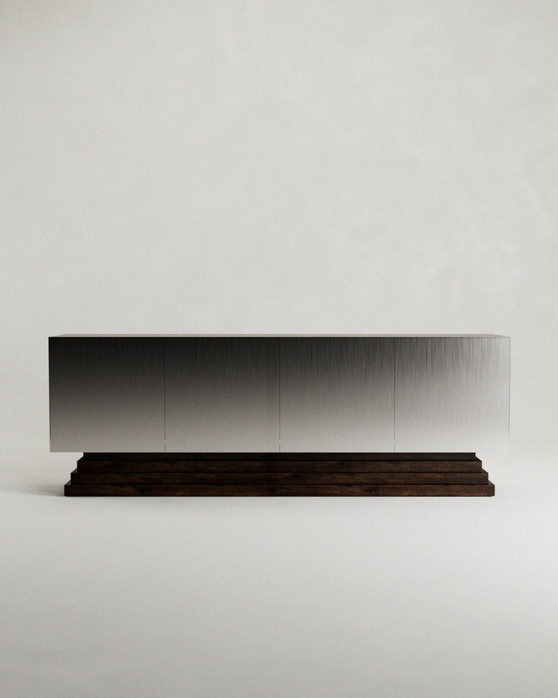 The 'Fragua' Sideboard by Siete Studio features a sleek modern design with a metallic brushed surface atop a dark tiered walnut base, showcasing minimalist design and artisanal craftsmanship against a plain white background.