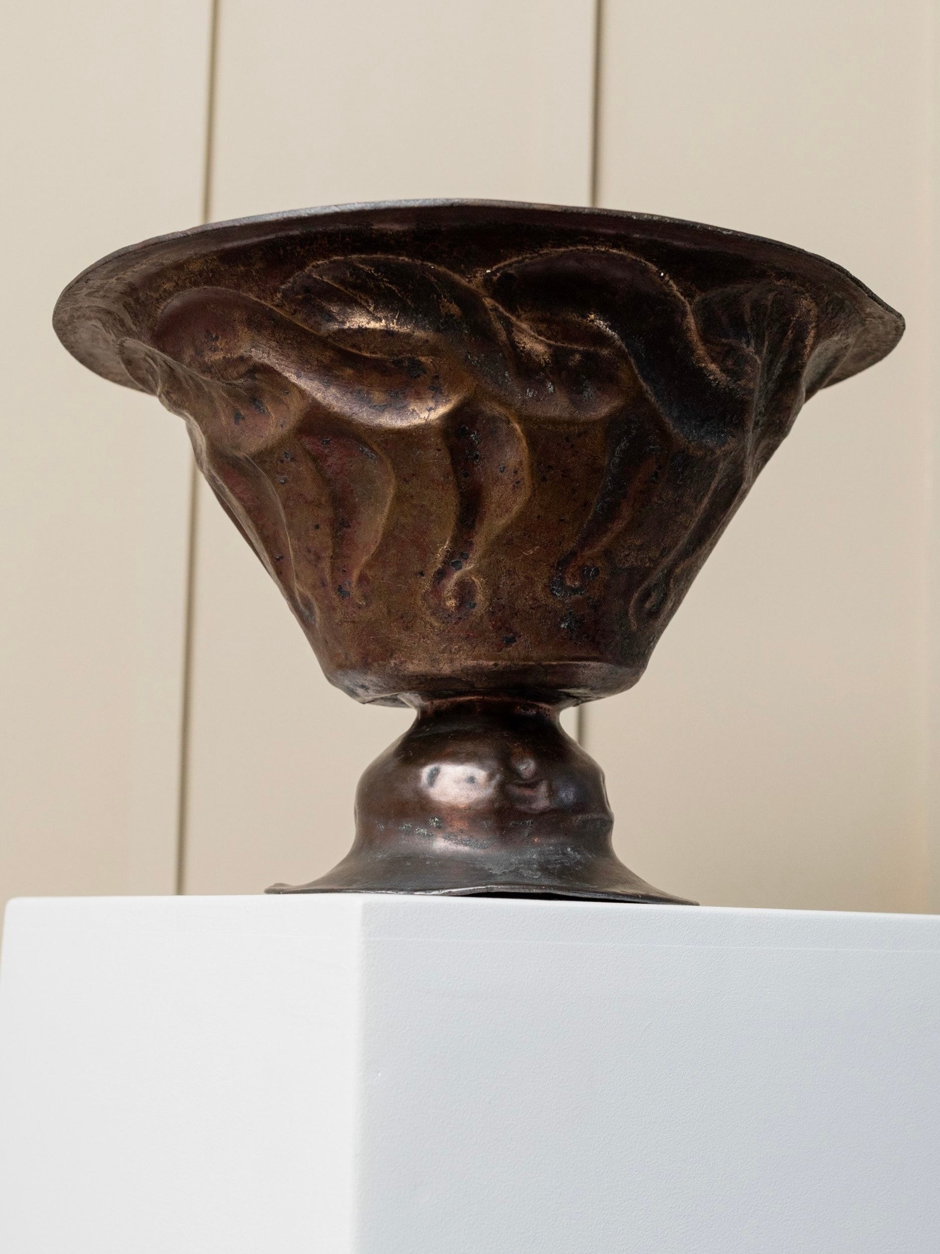 An intricately hand-carved, vintage-look Antique Fruit Bowl made of copper by Bottega Jacobs is displayed on a white pedestal against a neutral background, showcasing its wide, flared rim and narrow, rounded base.