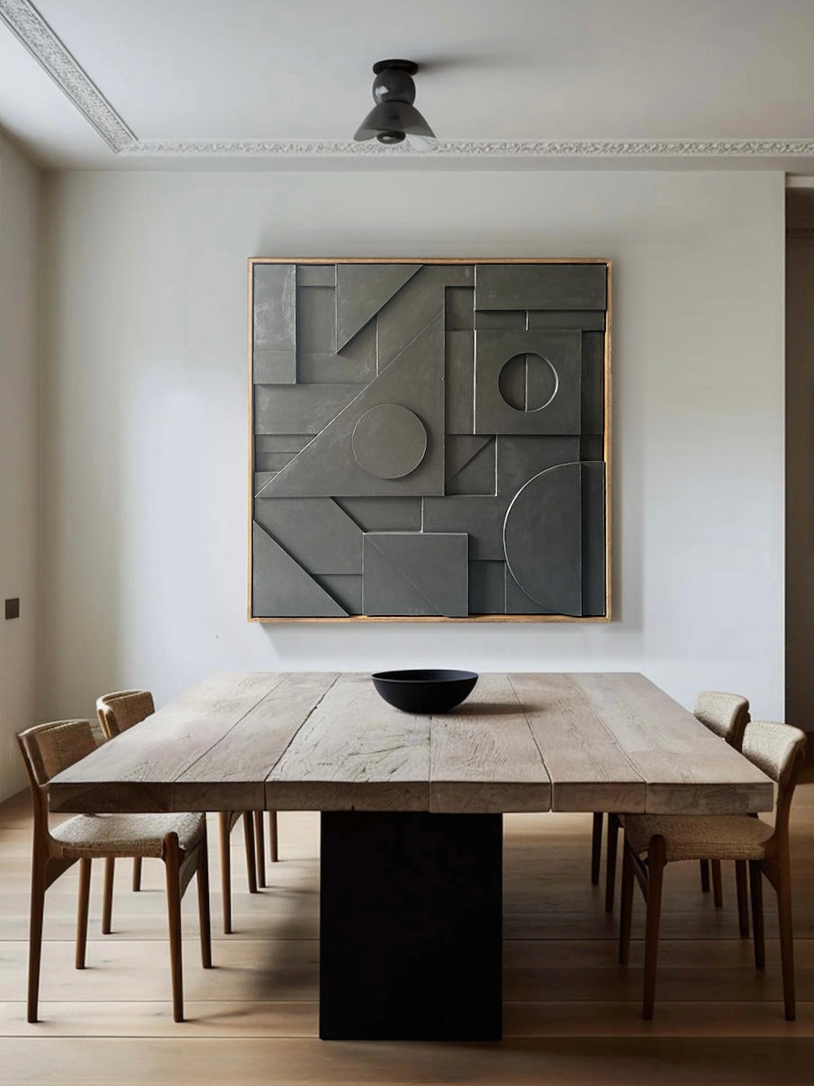 In a minimalist dining room, a Bauhaus-inspired wooden table with a dark base is encircled by six woven chairs. A Sean Thornhill Composition147 Sculpture adorns the wall, complemented by the wooden floor and a small black ceiling light above.