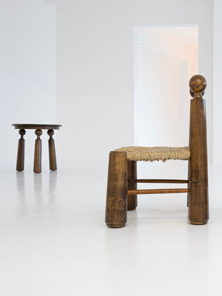 A Set of 2 Chairs and 1 Table by Charles Dudouyt from the 1940s, offered by antibeige, features wooden chairs with woven seats and thick cylindrical legs. The solid oak table complements the chairs, enhancing the minimalistic white interior of the restored room.