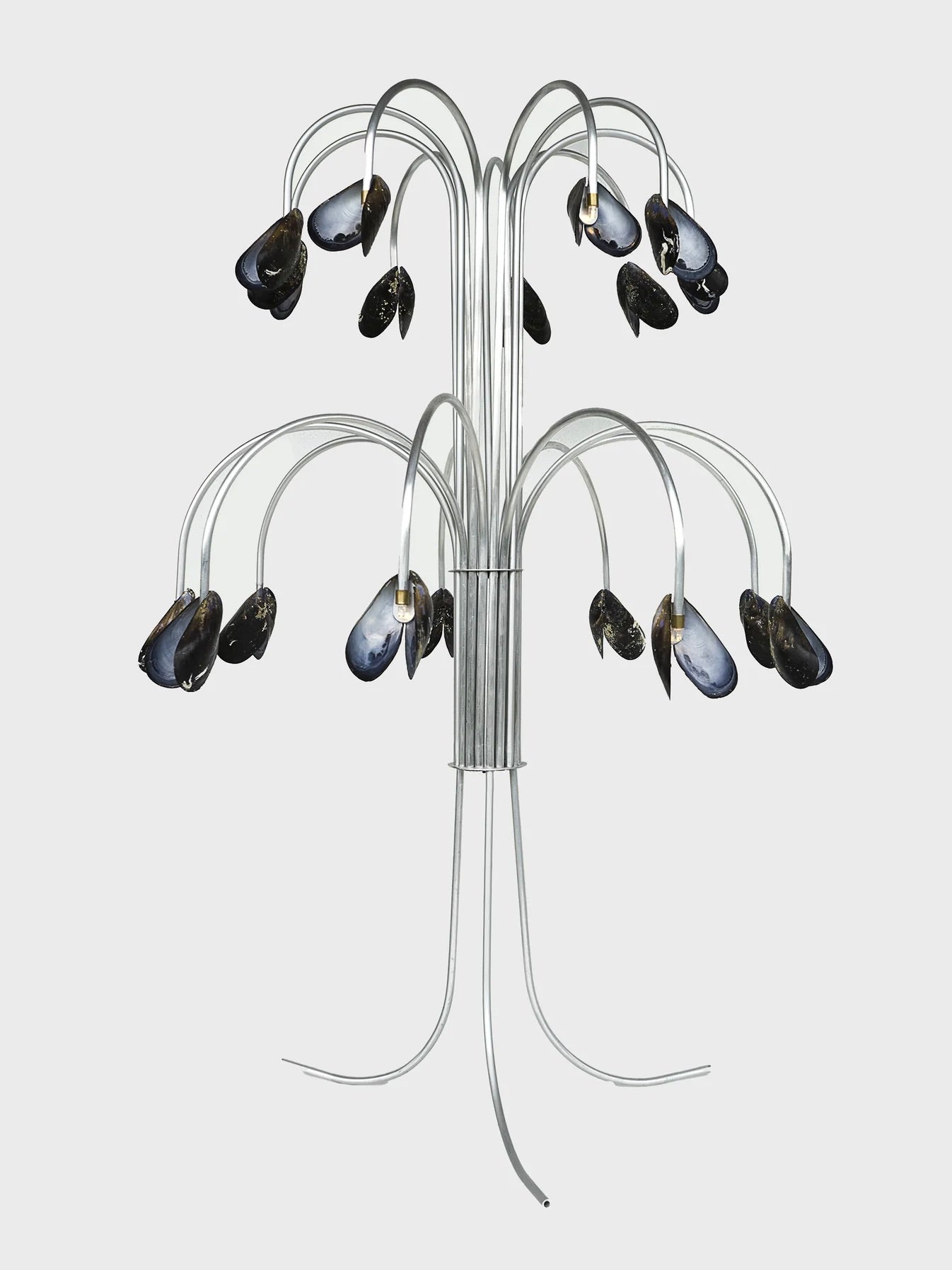 The "Shell Light" by Touch With Eyes is a handmade sculpture featuring thin metal branches adorned with blue-black mussel shells that glimmer like mother-of-pearl. It elegantly stands on a sleek metal base, offering an abstract and modern aesthetic.