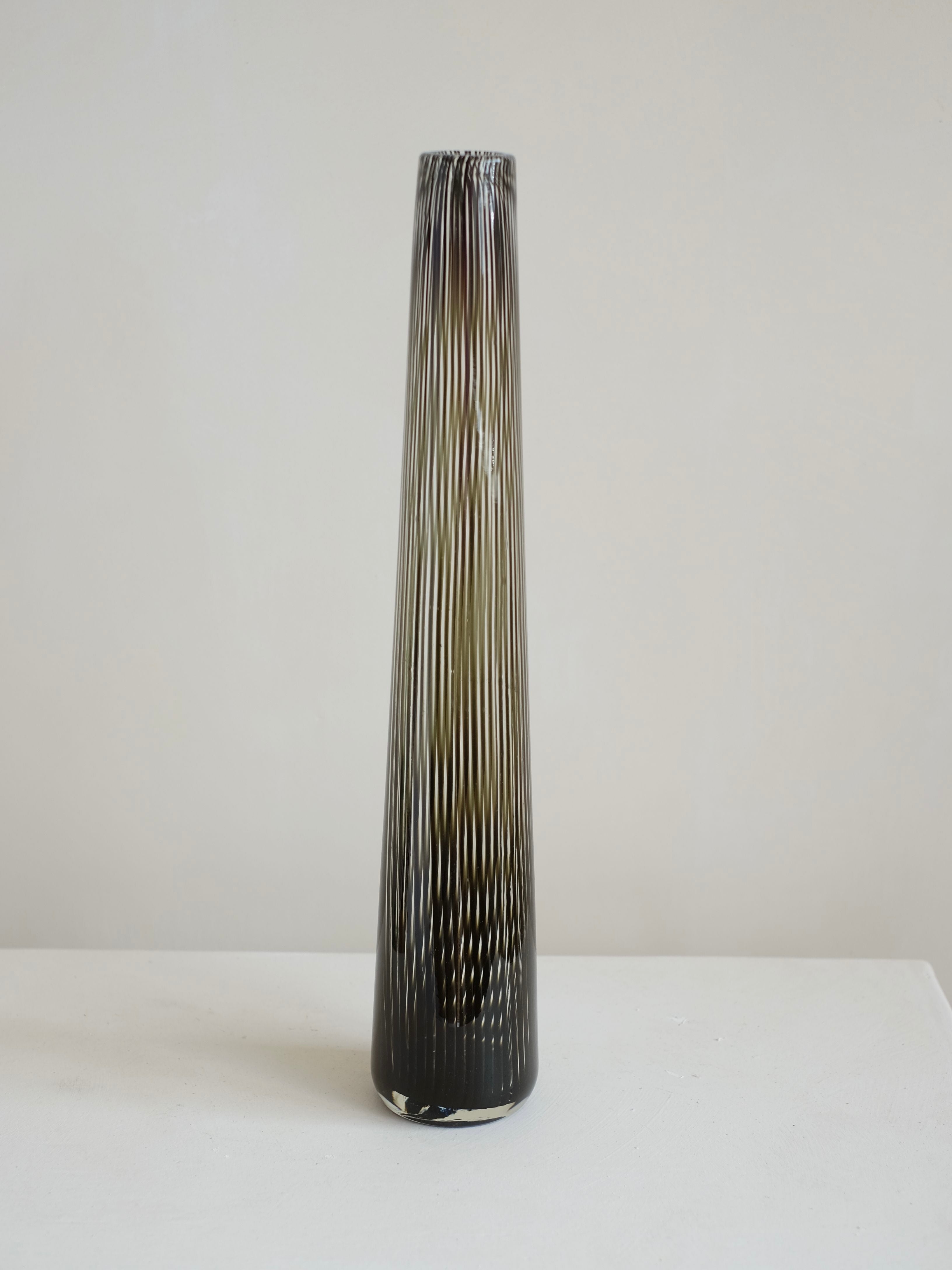 An Italian Murano Vase from 1970 by septembre studios stands tall and slender on a light-colored surface against a plain background. Featuring a black and white striped pattern, its narrow neck gracefully widens towards the base, emphasizing an elegant, modern appearance reminiscent of Italian glasswork.