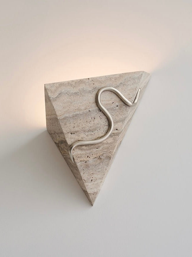 Introducing the Therapeutic Wall Light 3 by Mariza Galani—a handcrafted, wall-mounted triangular light fixture made of elegant silver travertine. It features an artistic metal squiggle that gracefully runs along the front. This therapeutic sconce emits a warm, subtle glow from behind the fixture, creating a soothing ambiance.