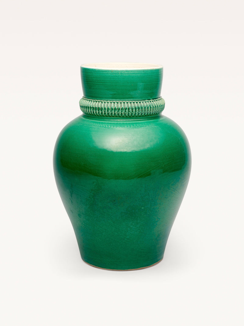 This Galerie MLS piece, reminiscent of Pol Chambost’s style, is a glossy green ceramic vase featuring a wide, rounded body and narrow neck with a decorative, textured band set against a plain white background.