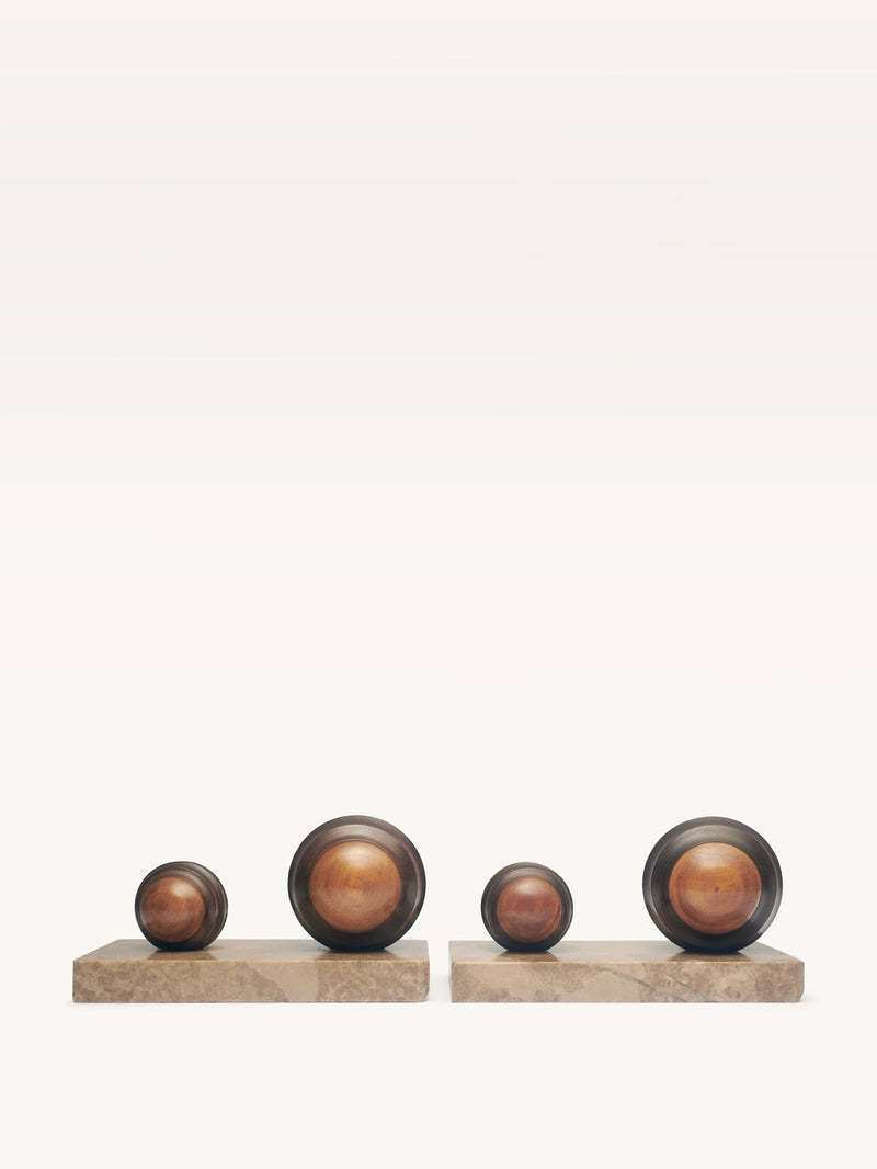 Two rectangular stone bases from Galerie MLS support a pair of smooth, polished Art Deco spheres in varying sizes. These modernist sculptures display natural color variations against a plain background, highlighting their timeless elegance.