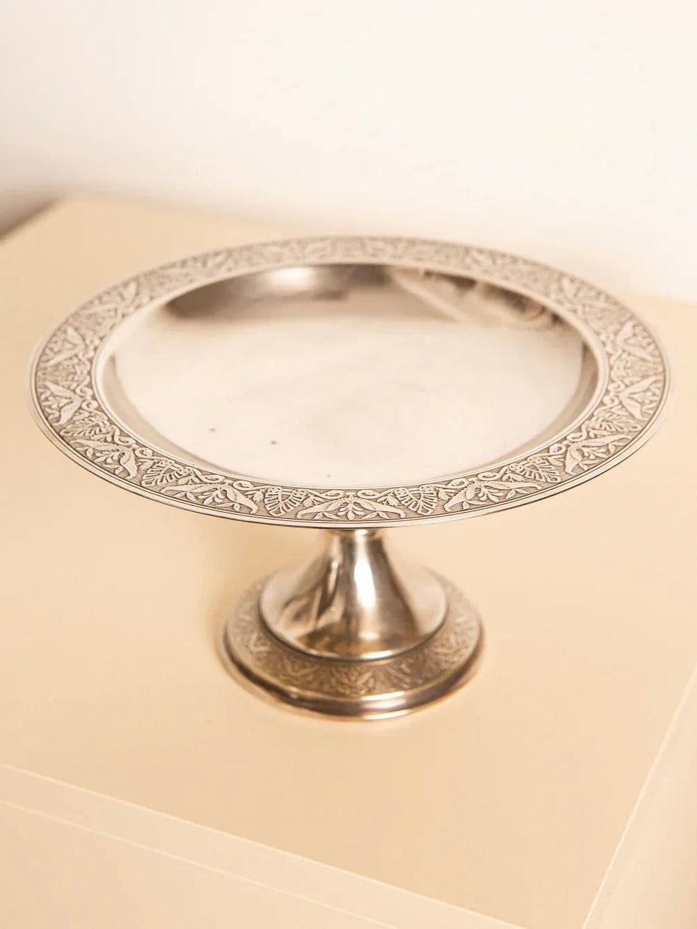 Presenting the Engraved Silver Plated Fruit Basket 60's by Treaptyque, this decorative piece showcases a retro style with its intricate patterns on the rim and base. The design reflects the elegance of 1960s aesthetics, beautifully displayed on a light-colored surface.