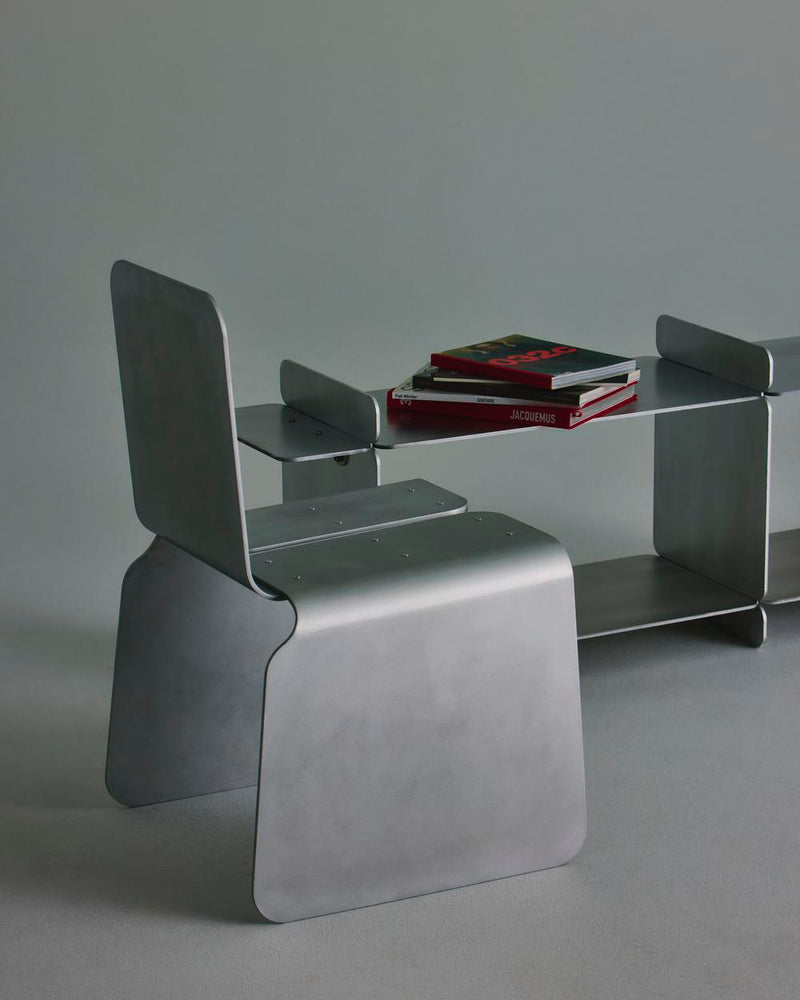 Modern glass console table with curved metal chair in minimalist setting