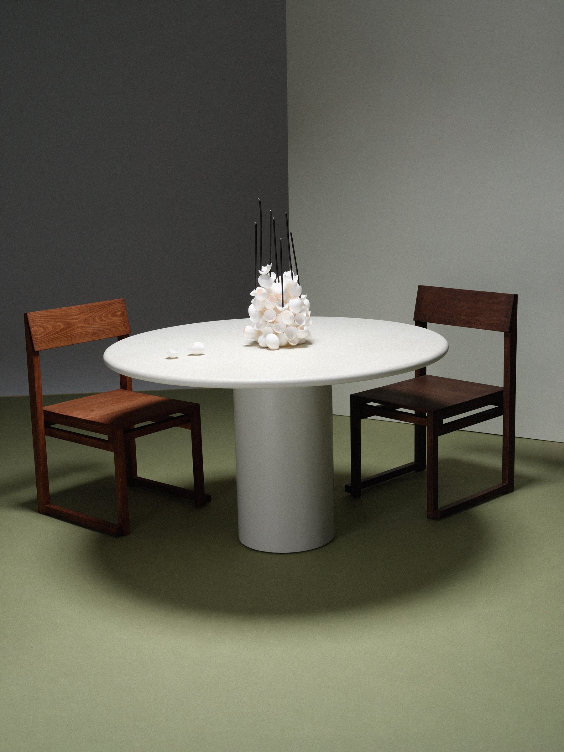 Gio Dining Table — side angle with round white surface and wooden chairs