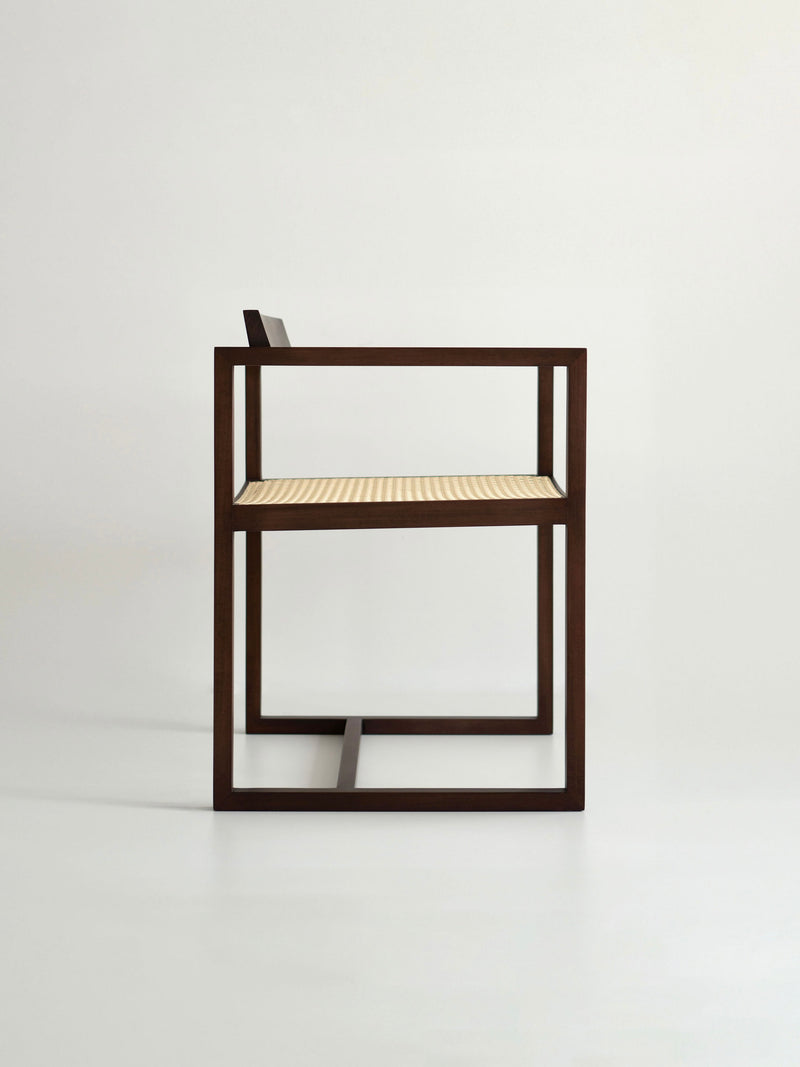 The "Amélia" Armchair by Andre Grippi features a modern, minimalist design with a dark wooden frame and a light woven straw seat, shown in profile against a plain white background.