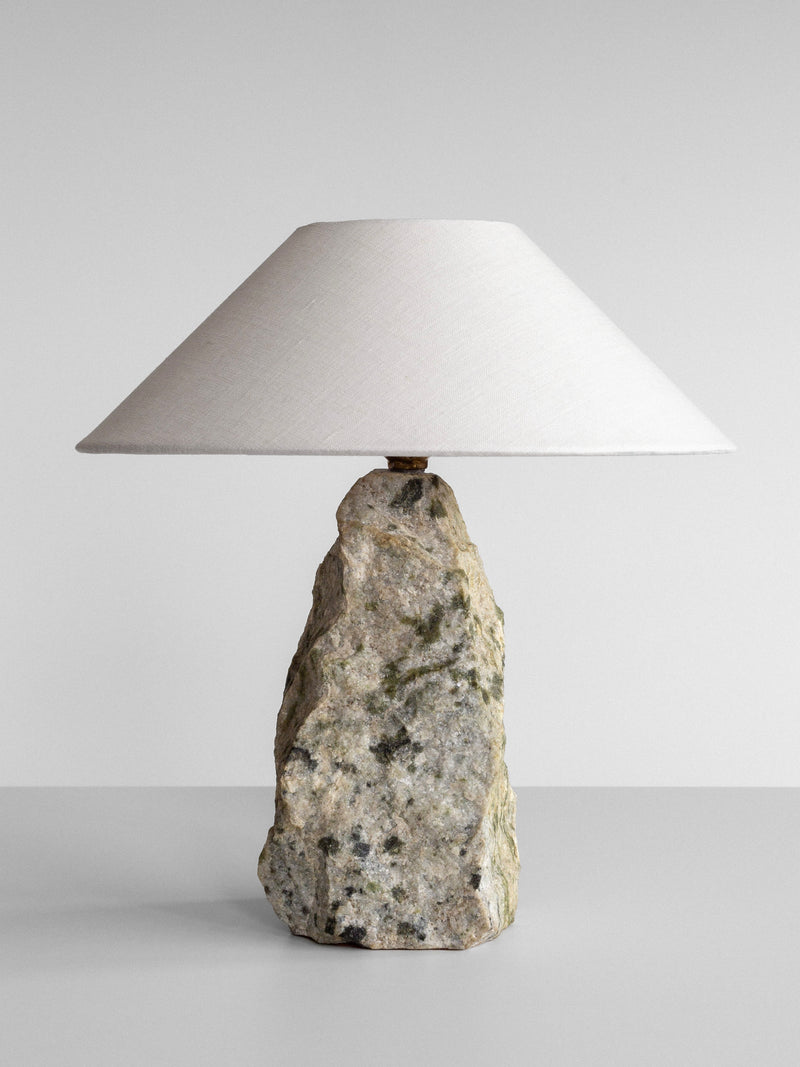 The Spigel Marble Stone Table Lamp, with its stone base and conical white lampshade, stands elegantly against a gray background.