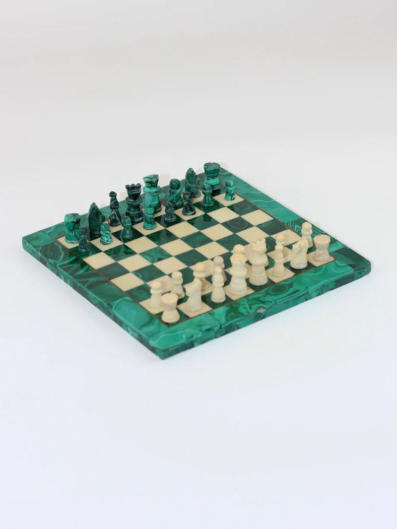 The Malachite And Marble Chess set from Boga Avante Shop presents a vintage charm, featuring handmade malachite chess pieces on an elegant green and white marble chessboard. The pieces are ready for battle, with the green positioned on the left and the white on the right, all beautifully arranged on a light gray surface.