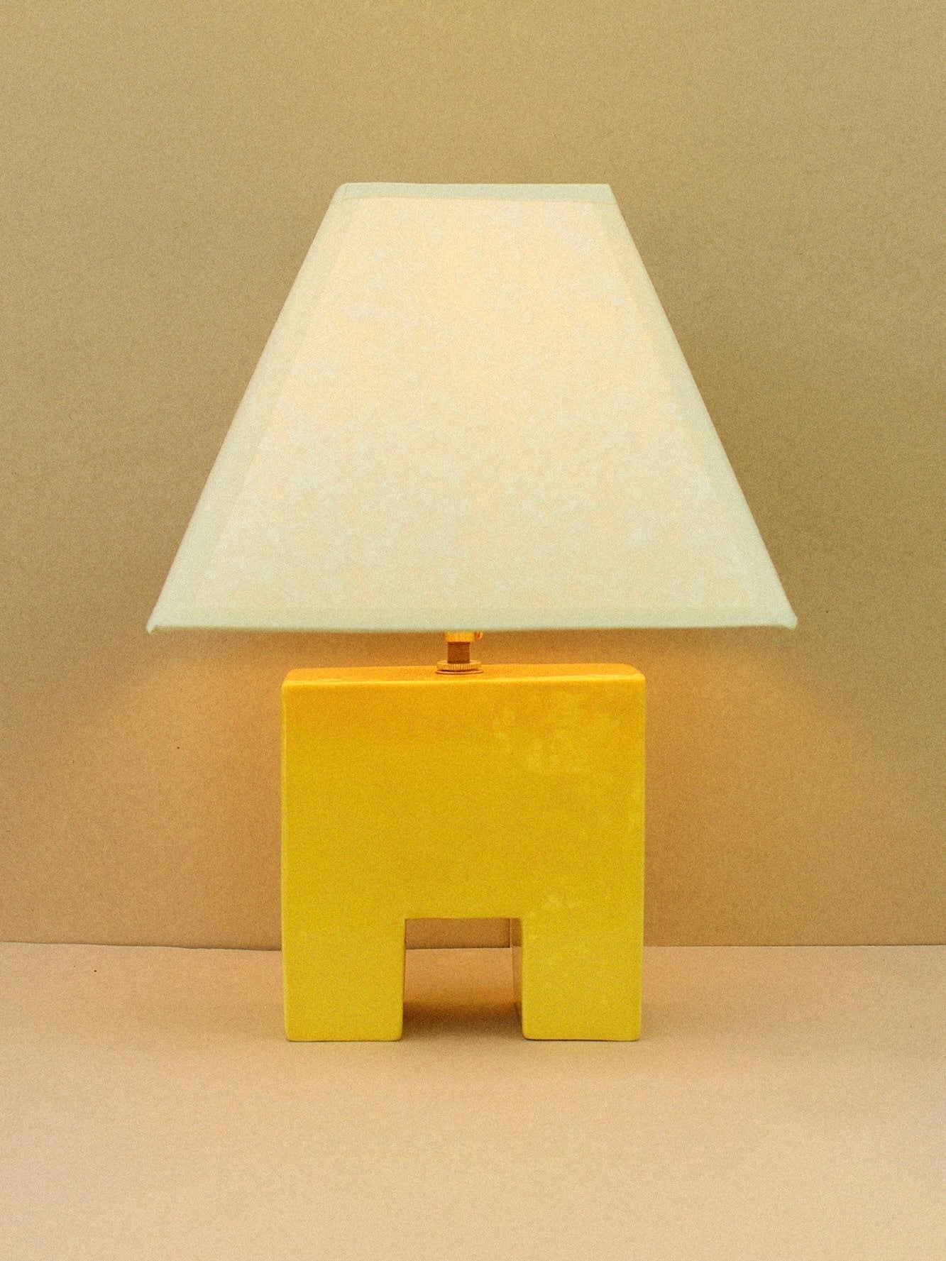 The Cristo Lamp (Sol) by Casa Veronica features a hand-built, rectangular yellow ceramic base and a wide white custom shade, shown against a plain beige background.