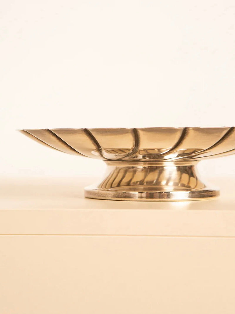 The Silver-plated Bowl 60s by Treaptyque exudes timeless elegance with its raised base and fluted design, gracefully showcased on a light-colored surface against a plain background.