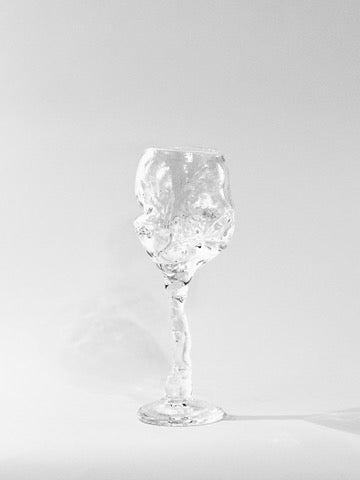 The Hand Blown Freeform Wine Glass from Szkło Studio features a uniquely shaped silver bowl with a textured, twisted stem against a white background. Handcrafted in the tradition of Polish glassware, its design emulates flowing liquid, blending elegance with abstract form.