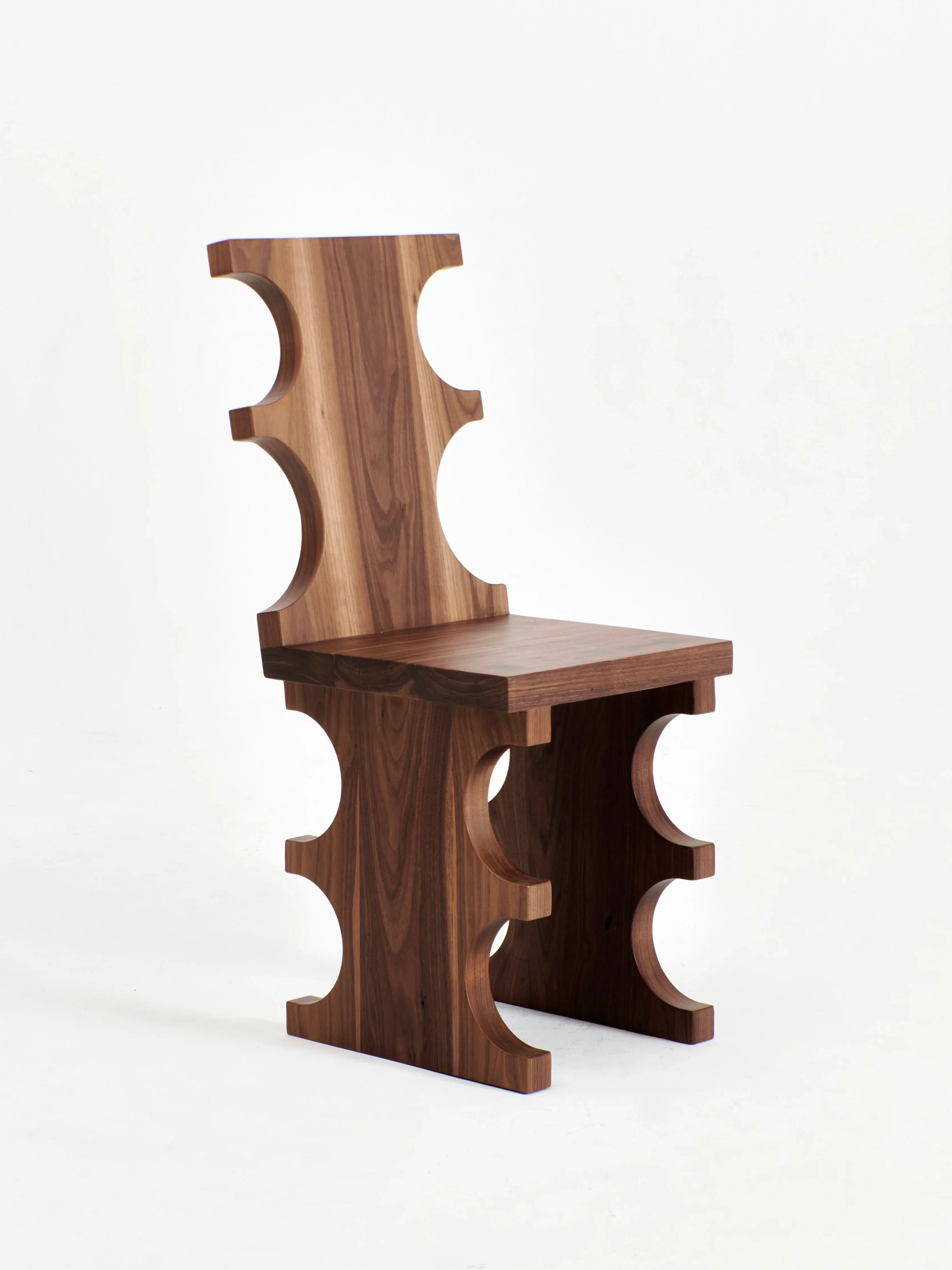 The Portugal Chair No 7 by Project 213A is a modern piece made from solid walnut, featuring a unique design with multiple arch-like cutouts along the backrest, seat, and legs. Crafted by skilled artisans, it boasts a rich brown finish with natural wood grain patterns, standing elegantly against a plain white background.