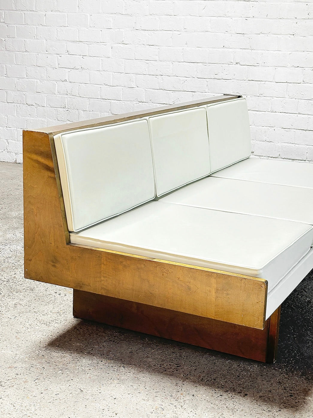 The room features a French Modernist Sofa Set in White Leather from the 1950s by Introverso, complemented by white brick walls and a concrete floor. This mid-century piece boasts eco-leather upholstery and a wooden frame for a sleek, contemporary look.