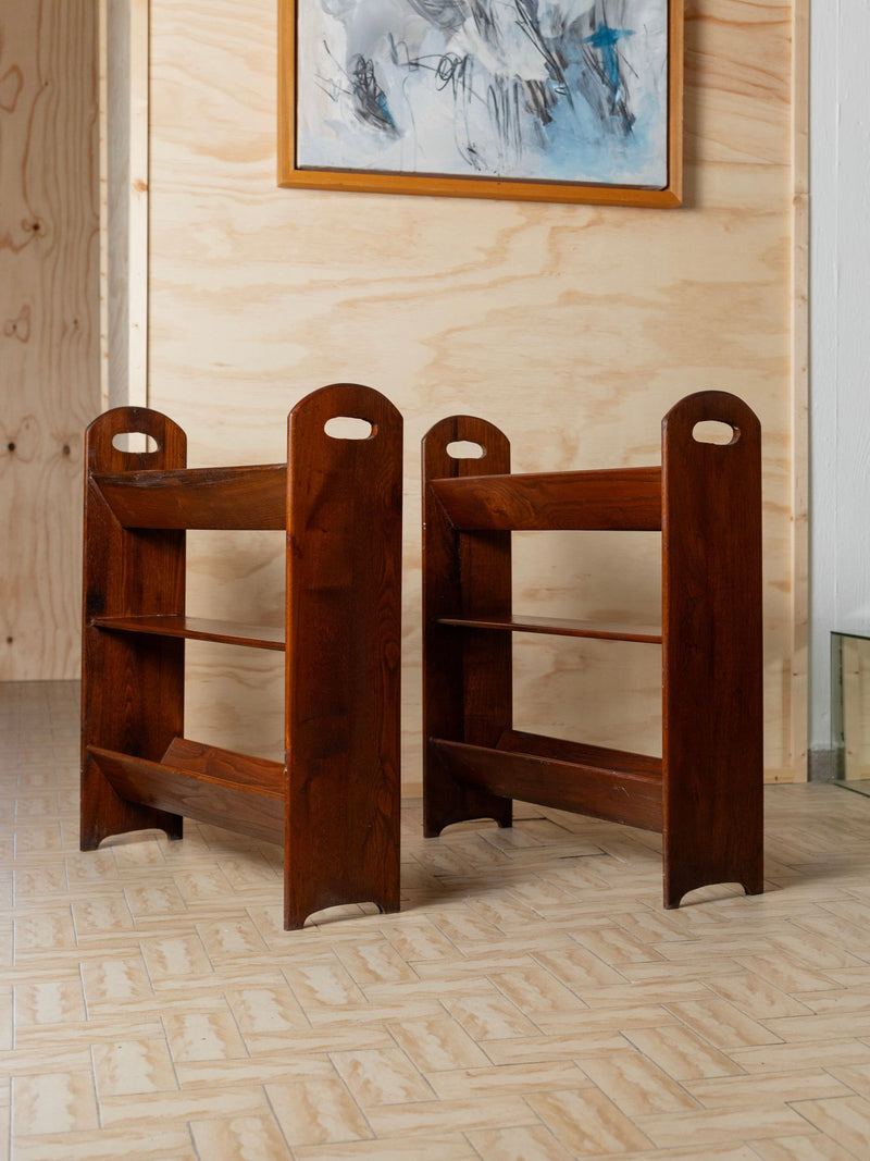 Two Bottega Jacobs vintage wood bookcases from 1960s Italy stand side by side on a tiled floor. A framed painting with abstract strokes hangs on a light wooden wall in the background, adding an artistic touch to the display.