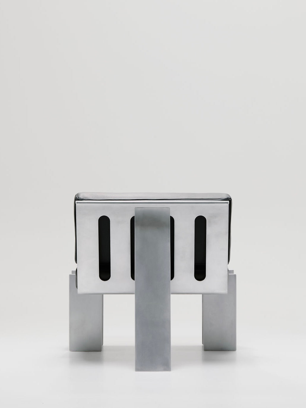 The Marquel Williams Beam Lounge Chair is a minimalist marvel with an angular design, rectangular backrest, and waxed aluminum construction. Its chunky legs stand out against a plain white background.