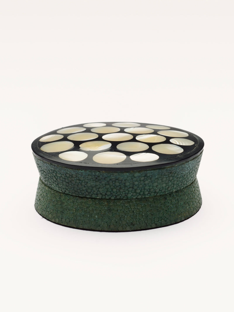 The Small Shagreen Pearl Box by Galerie MLS is a round green box with a black lid, decorated with cream circular inlays arranged in a grid pattern.