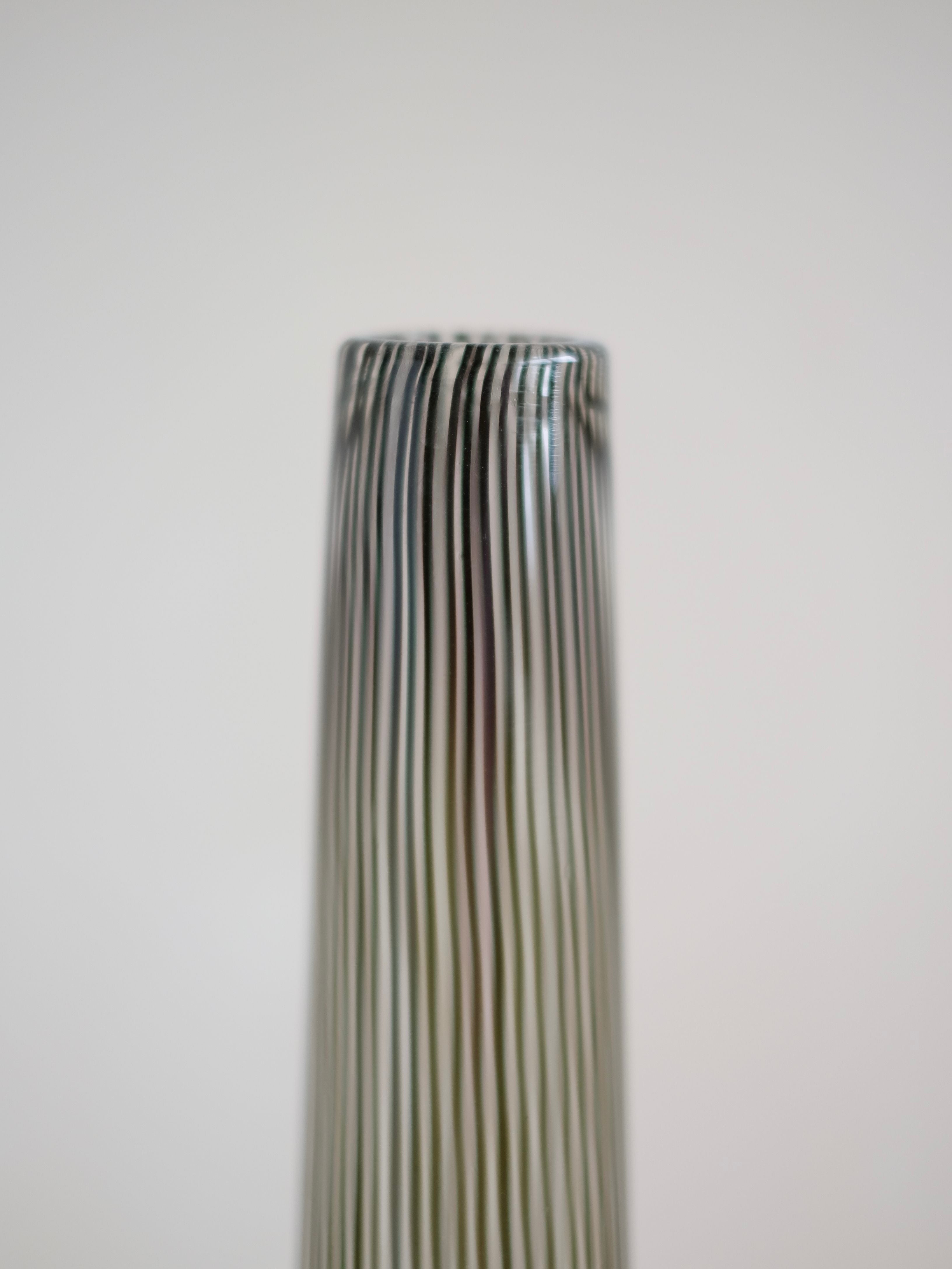 Close-up of the top of a tall, thin, cylindrical Italian Murano Vase from 1970 by septembre studios, featuring vertical black and white stripes against a neutral background to highlight its vintage artistry.