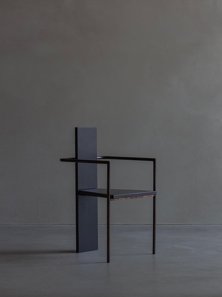 The Jonas Bohlin-CONCRETE black chair by Bicci de' Medici features a minimalist design with a sleek dark frame, tall backrest, and armrests against a plain gray background. Its geometric structure epitomizes modern allure, merging artistry with bold minimalism.