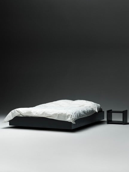 Black floating platform bed with white bedding and minimal nightstand