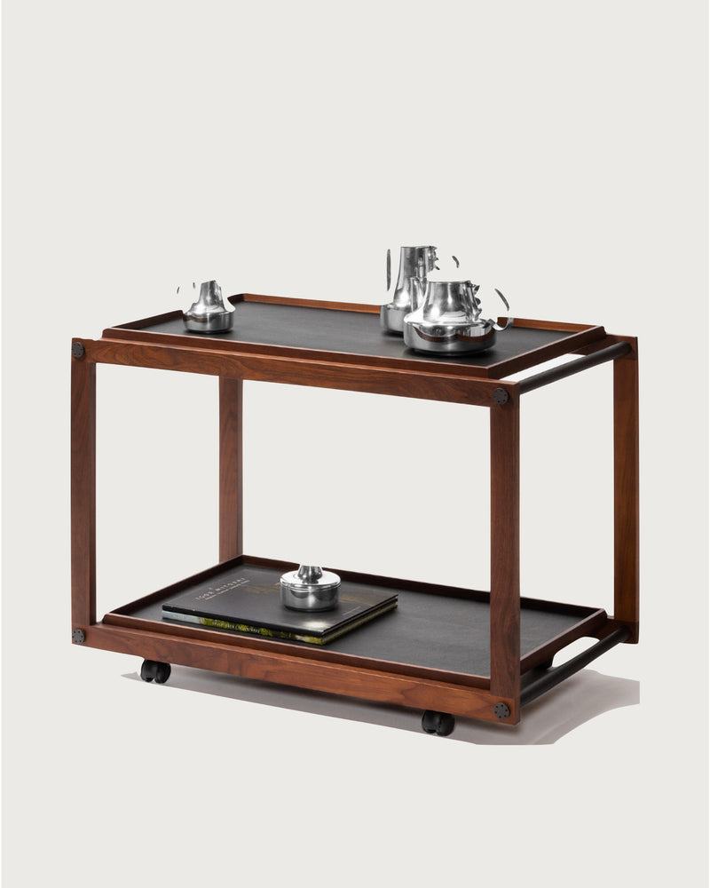 Modern walnut serving trolley with black shelves and silver tea set
