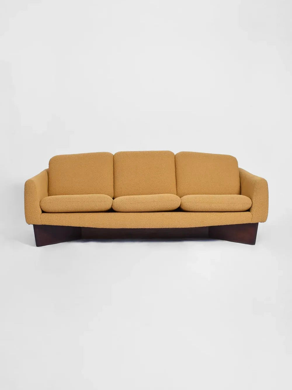 A Dangles and Defrance Yellow Sofa from the 1960s, crafted by Barracuda Interiors, features a mustard-colored bouclé fabric and plush cushions atop a dark wooden base, sitting elegantly against a plain white background.