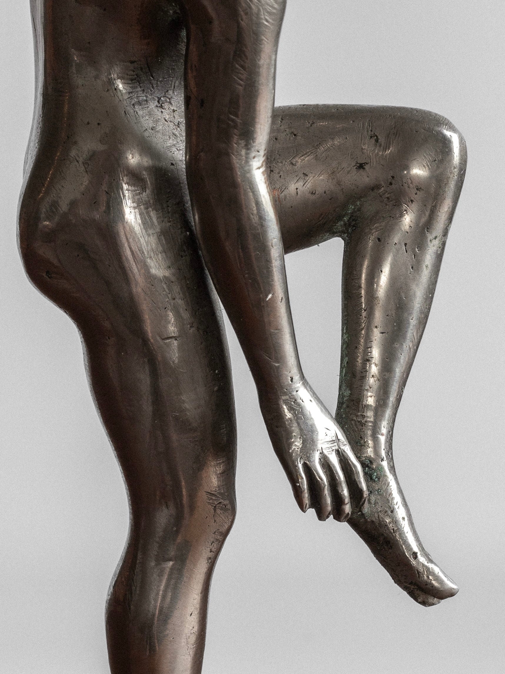 The Spigel Elegant Metal Sculpture, 1930s, features a highly polished pewter nude human figure balancing on one leg. The other leg is raised with the foot held by one of the hands, and the sculpture's detailed muscle definition stands out against a plain gray background, evoking a Swedish neoclassical design from the 1930s.