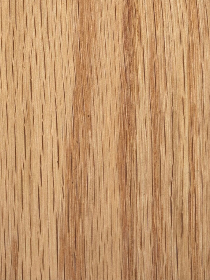 Close-up of a wooden surface, evocative of Obstacles' Marina Sofa solid oak frame, highlighting natural grain patterns in a warm, light brown color with subtle texture and hue variations.