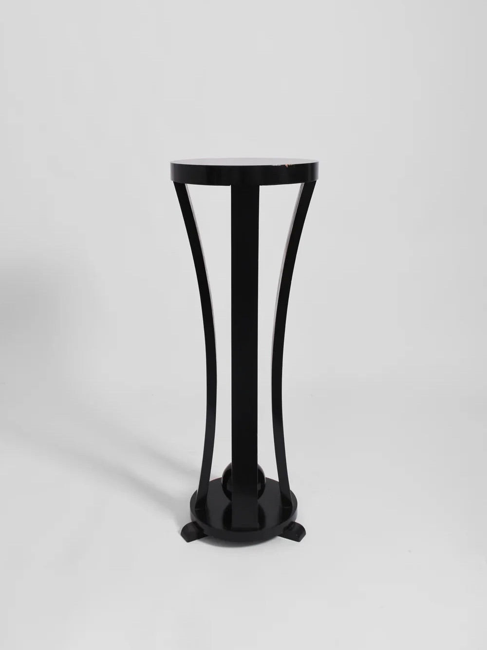 A stylish black wooden pedestal from Barracuda Interiors, featuring a round top and elegantly curved legs, designed in the 1960s, is set against a plain white background.