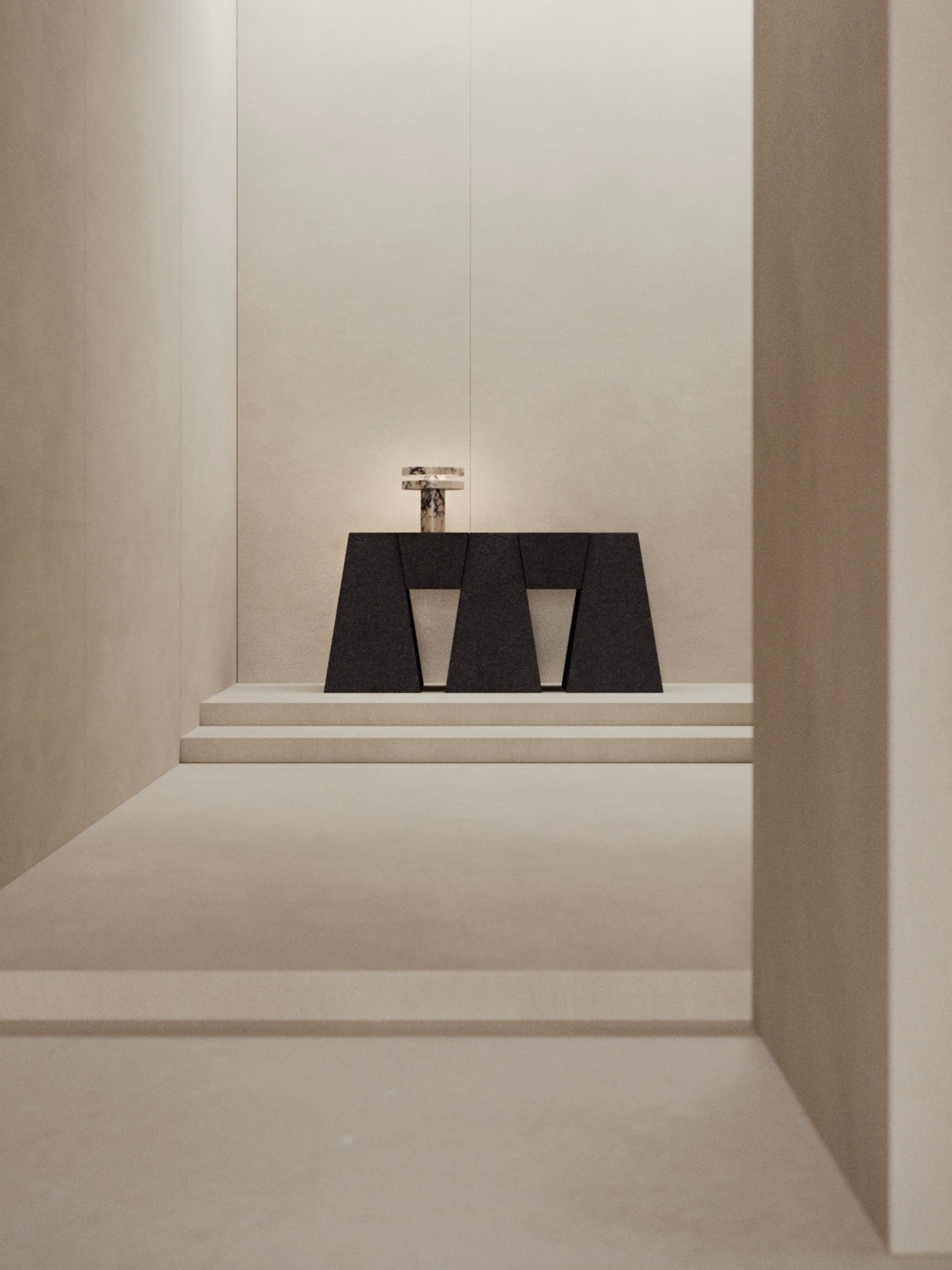 A minimalist interior features the M_006 Walnut Console by Monolith in a narrow corridor. A small sculpture graces its surface amid muted beige tones and sharp lines, with soft lighting enhancing the serene ambiance.