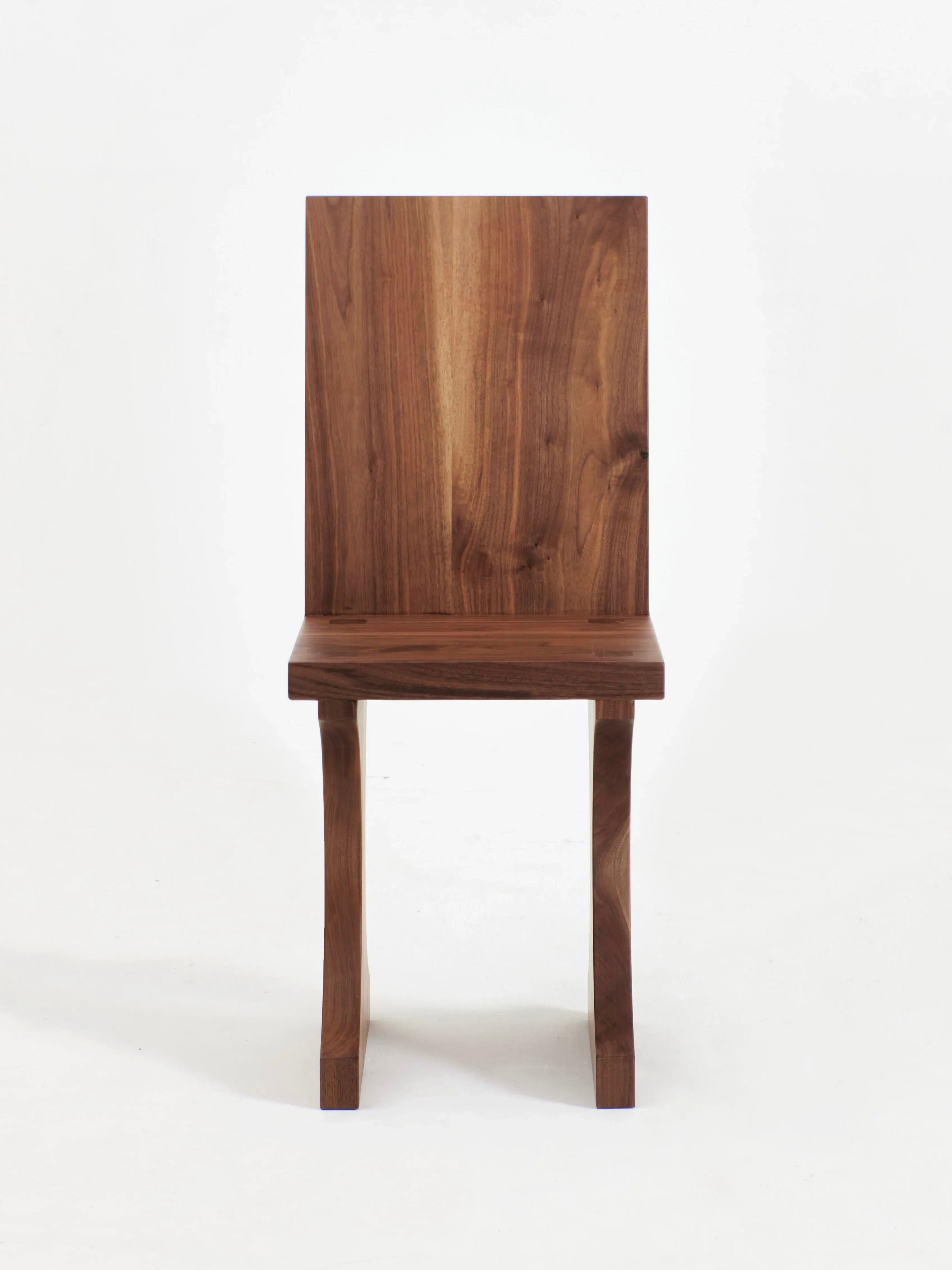 A simple wooden chair with a rectangular backrest and seat, featuring two slightly curved front legs. Handcrafted from solid walnut, the Project 213A Portugal Chair No 3 boasts a smooth finish with a natural grain pattern. The background is white.