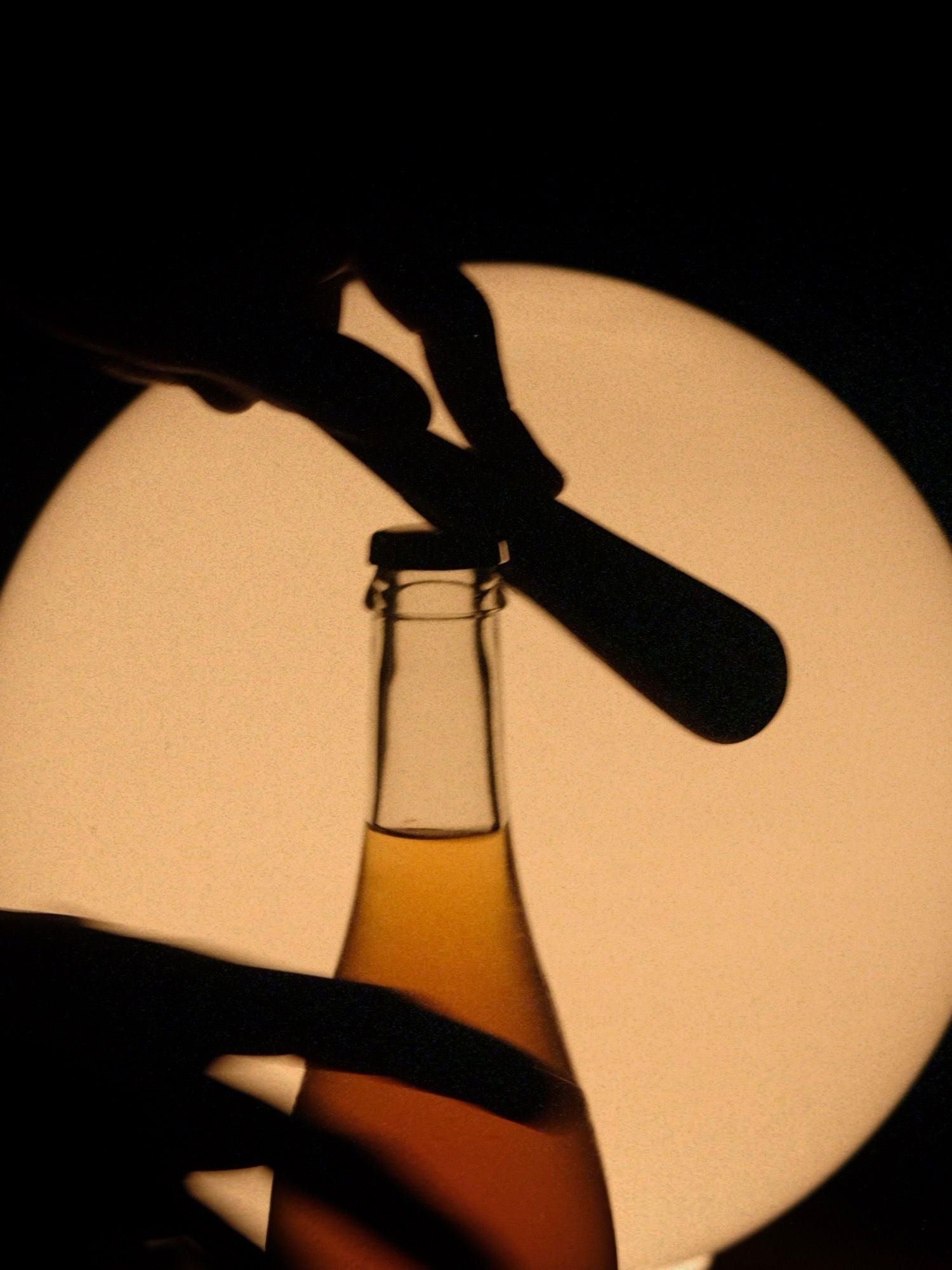 Silhouette of hands using the "Gota" Bottle Opener by Pedro Avila against a warm light background, highlighting the anticipation of enjoying this limited edition release.