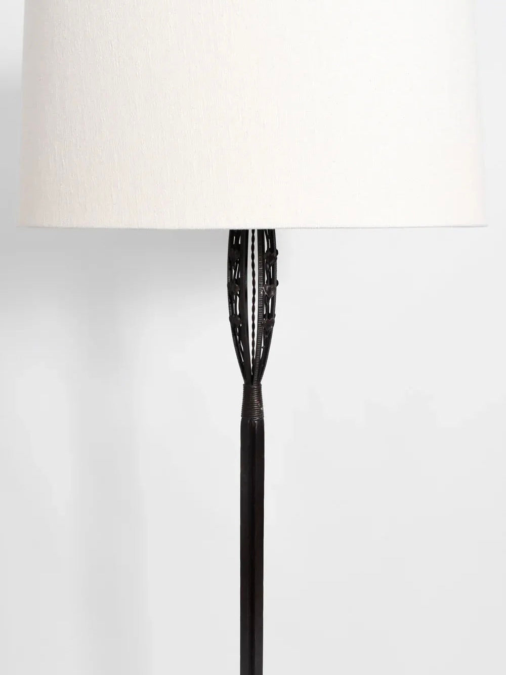 The Arts Deco Iron Floor Lamp, 1930s by Barracuda Interiors exudes elegance with its black textured metal base and large white fabric lampshade. The base features intricate woven detailing near the top, capturing the timeless allure of Gingko decor as it stands gracefully against a plain white background.