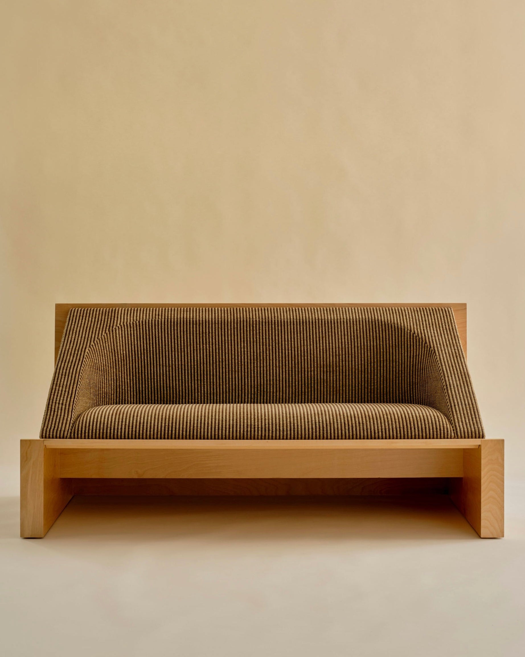 The 'Perceptions' Sofa Bench by Known Work features a modern wooden frame with ribbed upholstery in neutral brown against a beige backdrop. Its minimalist design highlights clean lines and geometric shapes, embodying true minimalist values.