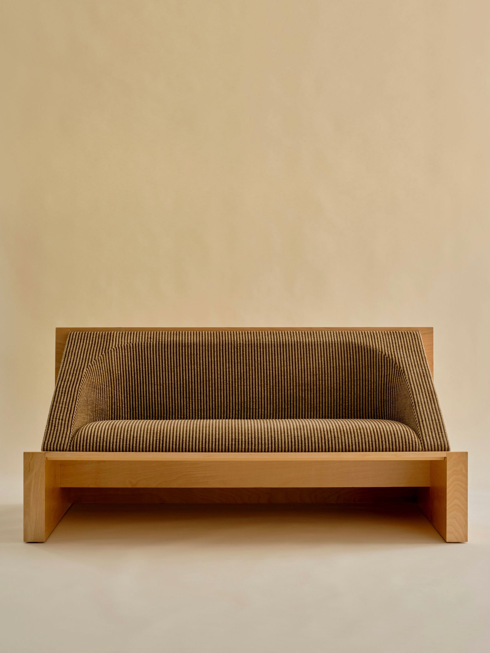 The 'Perceptions' Sofa Bench by Known Work features a modern wooden frame with ribbed upholstery in neutral brown against a beige backdrop. Its minimalist design highlights clean lines and geometric shapes, embodying true minimalist values.