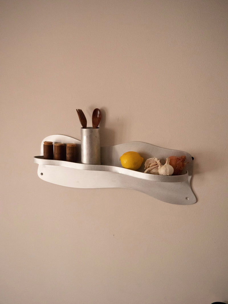 White wall-mounted kitchen shelf with spice jars and utensils