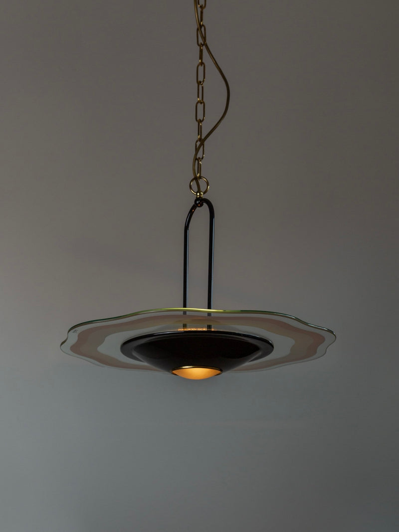 The Vintage Ceiling Lamp - 1980s Murano Glass by Bottega Jacobs showcases a UFO-shaped pendant light with a wavy Murano glass rim and a central glowing bulb. It elegantly hangs from a brass chain against a gray background, exuding mid-century design charm.