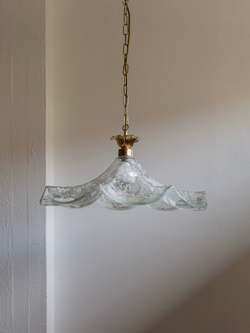 The Vintage Ceiling Lamp Murano 70s Italy by Bottega Jacobs features a wavy, translucent shade made from Murano glass, suspended from a brass chain against a plain, light-colored wall. The lighting accentuates the texture and patterns of the exquisite glasswork.