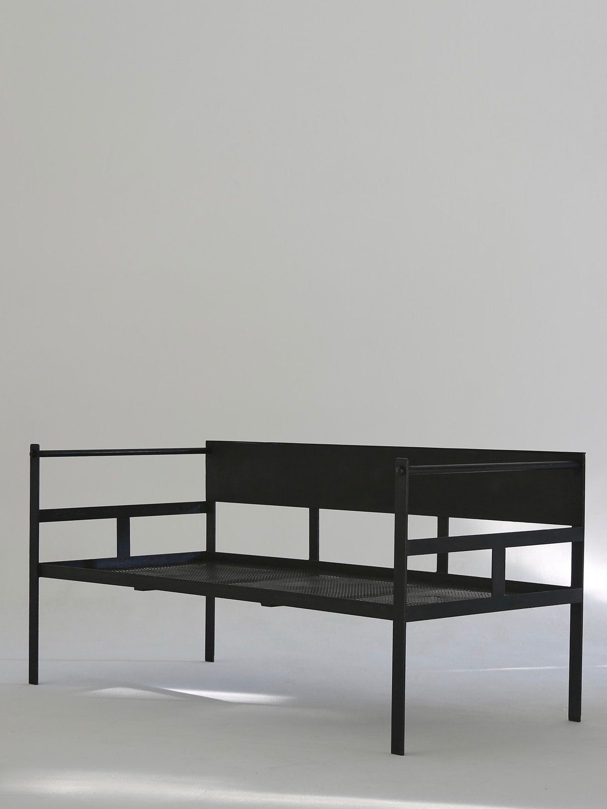 The Modernist Lounge Set by Ancien et Jolie features a minimalist black metal bench with a steel frame, flat seat and backrest, thin linear armrests, and legs. Its elegant, simple design is reminiscent of Mathieu Mategot's style and stands against a white backdrop.