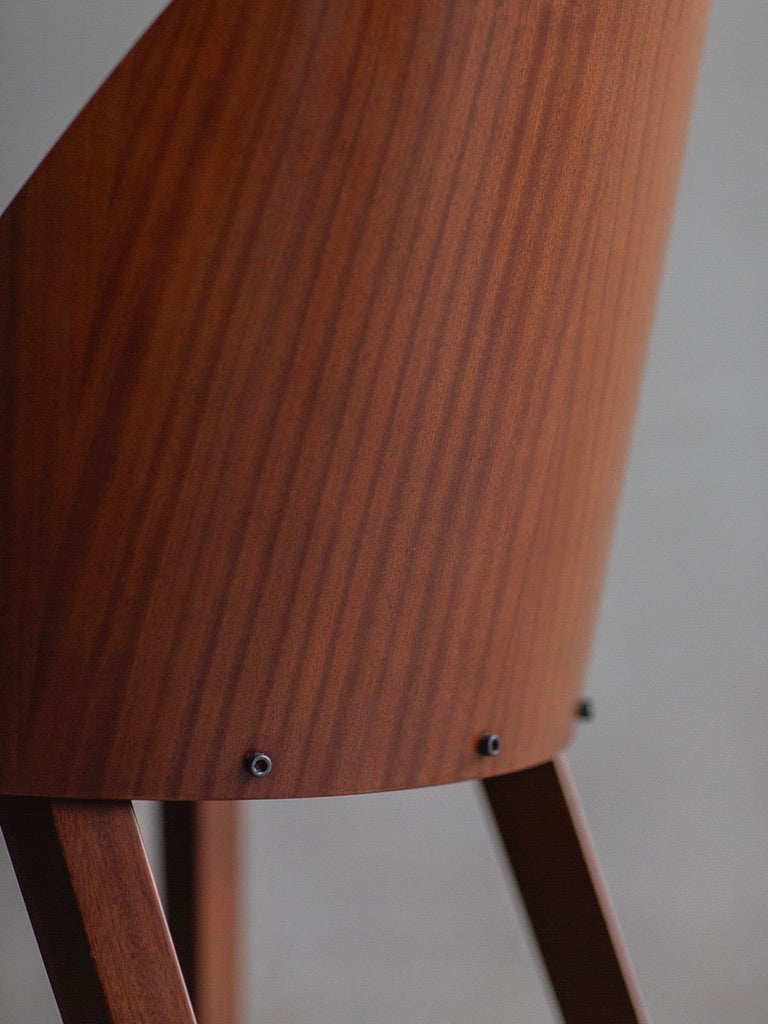 Close-up of a Bicci de' Medici Philippe Starck - Royalton 44 chair with a polished finish, featuring a backrest with subtle vertical grain patterns and black screws at the base. The partially visible legs complete its minimalist design, echoing those in the Royalton Hotel.