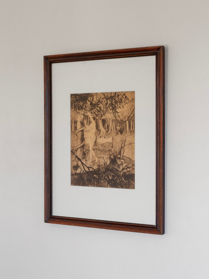 A framed etching titled "Adam & Eve" by Gaston Smidt, created in the 1900s using dry-needle technique, showcases nature with trees and shoreline. Part of Spigel's collection, it features a sepia tone in a dark rustic wooden frame against a light backdrop.